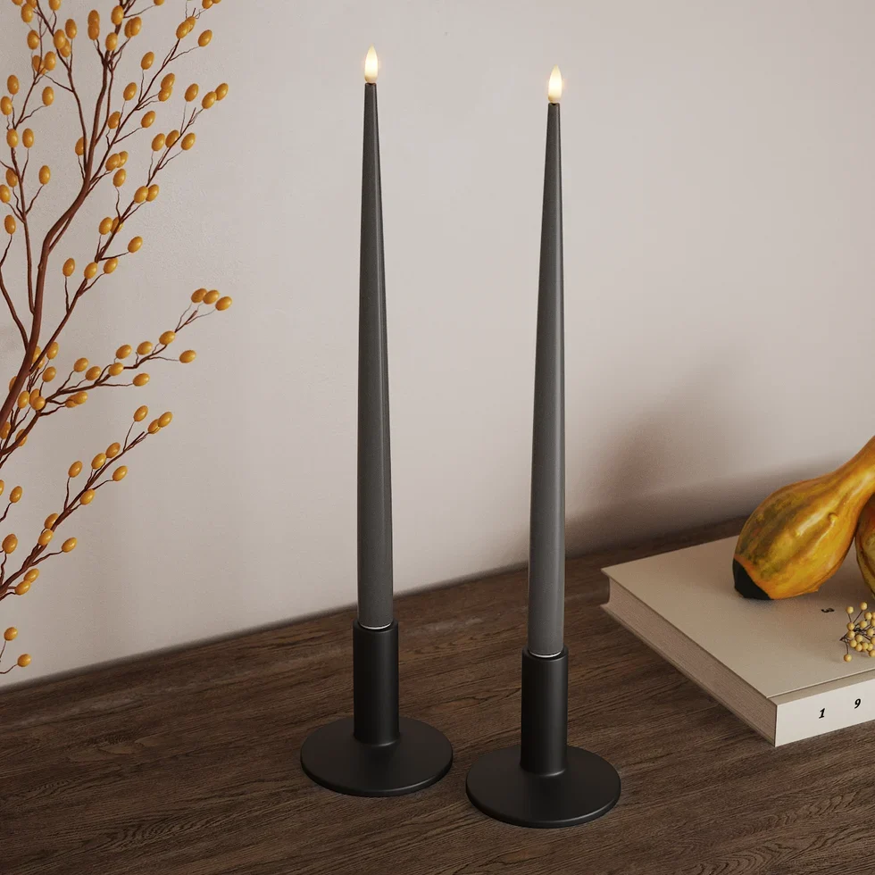 Graue LED-Stabkerzen in schwarzen Haltern auf einem Sideboard mit gelben Beerenzweigen und Kürbissen als Herbstdeko