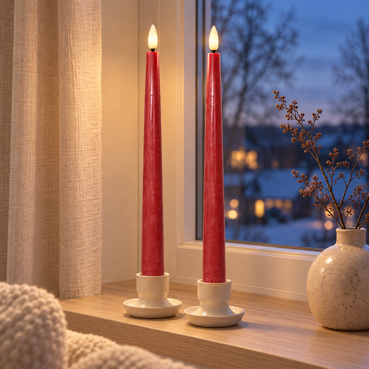Rote LED-Stabkerzen in Keramikkerzenhaltern auf der Fensterbank an einem Winterabend