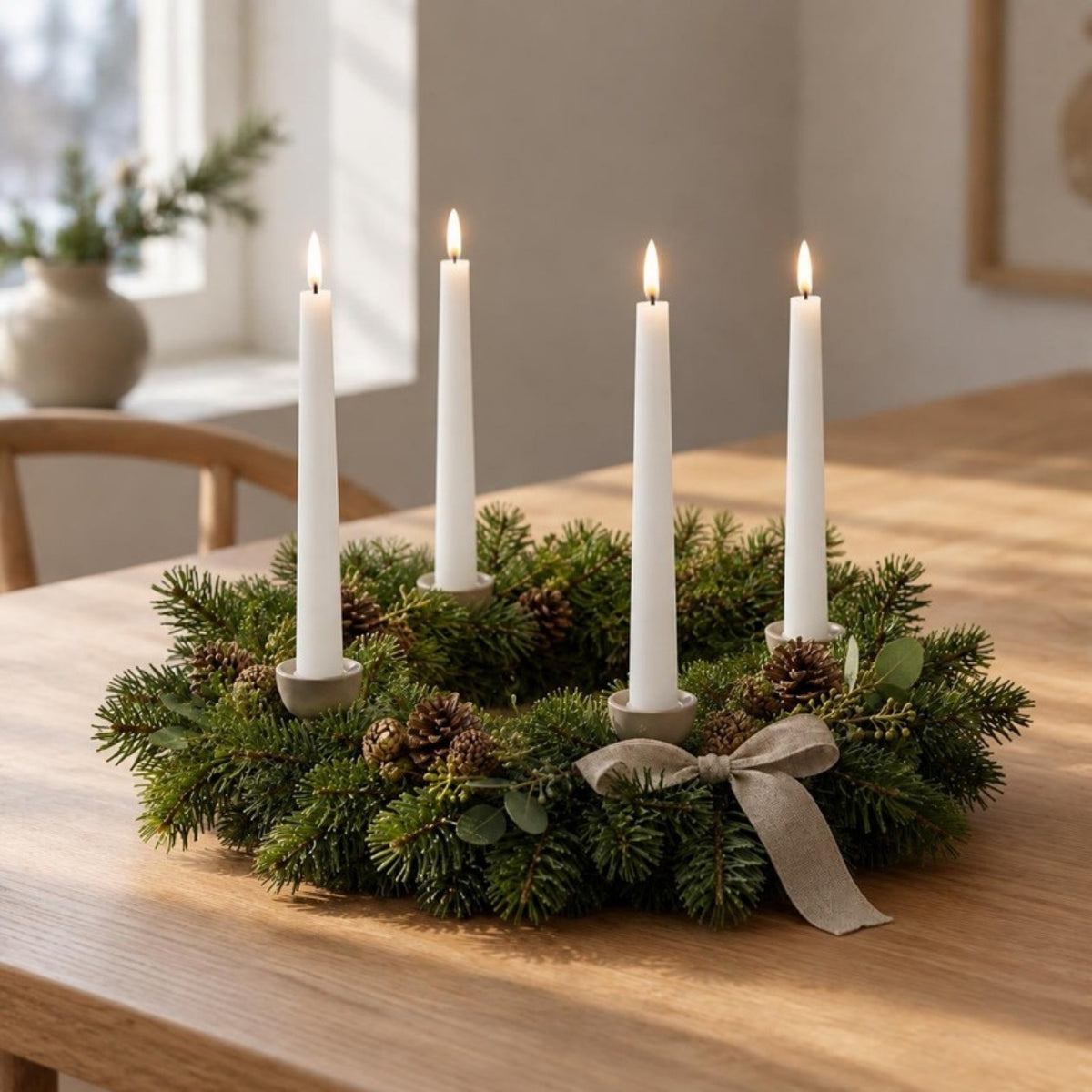 Vier weiße LED-Stabkerzen im Shiny-Pool-Look in einem Adventskranz aus Tannengrün mit Zapfen und Leinenschleife auf einem Holztisch