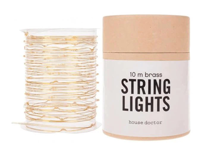 House Doctor Lichterkette aus Messing, 10 Meter, auf eine durchsichtige Spule gewickelt, neben der runden Kartonbox mit der Aufschrift "String Lights".
