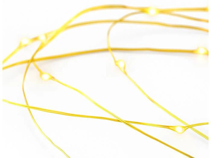 Nahaufnahme einer dünnen Lichterkette aus Messing mit kleinen, warmen LED-Lämpchen auf weißem Hintergrund.